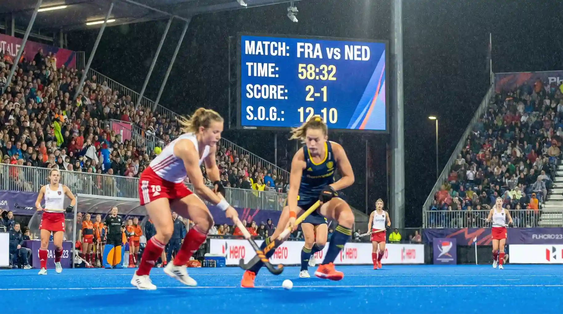 Hockeywedstrijd met scorebord op de achtergrond
